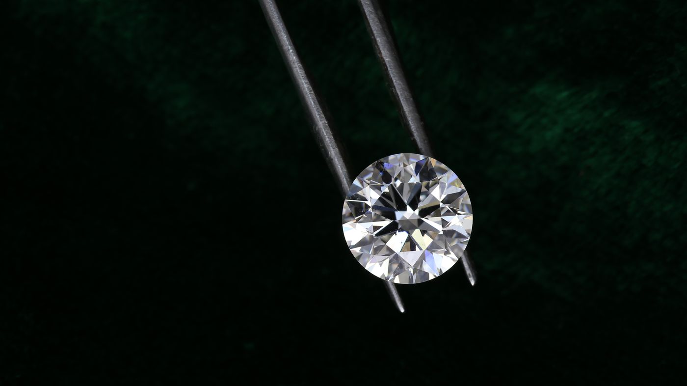 A round brilliant diamond held in tweezers