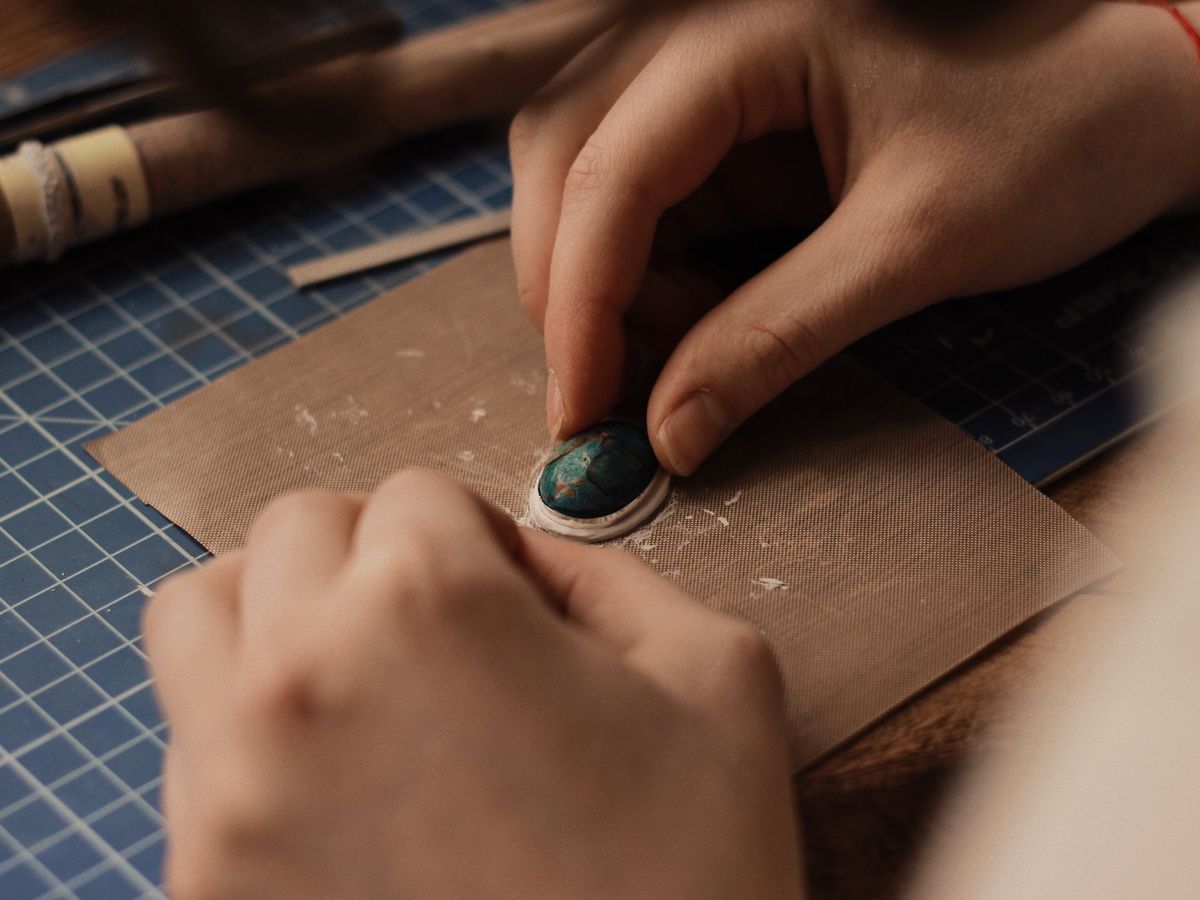 A craftsman's hands working a stone at the bench