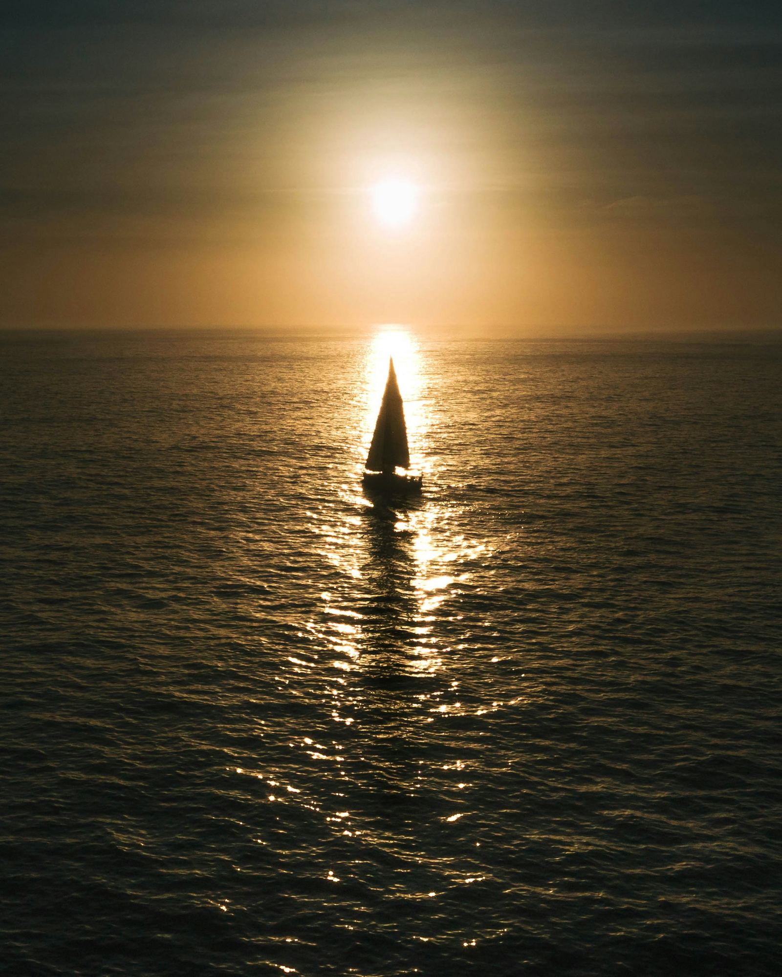 Sailboat on calm water at golden hour off Hout Bay, Cape Town